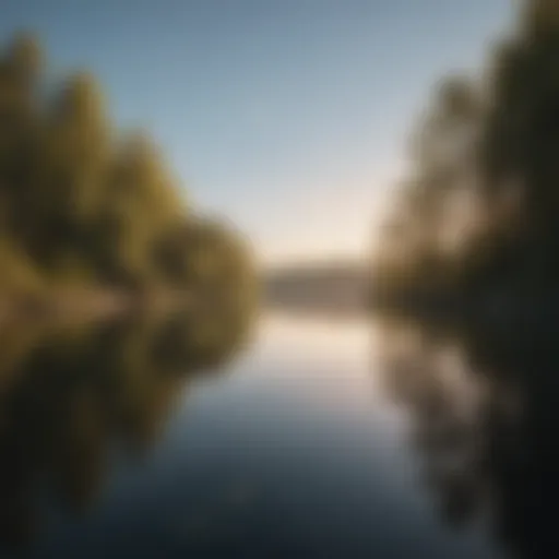 A serene landscape featuring a calm lake reflecting a clear sky